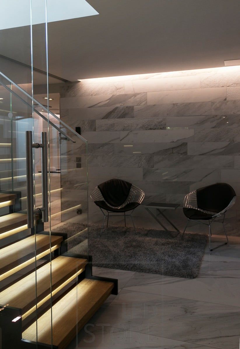 Indirect light between the ceiling and the wall and on the steps of the stairs.